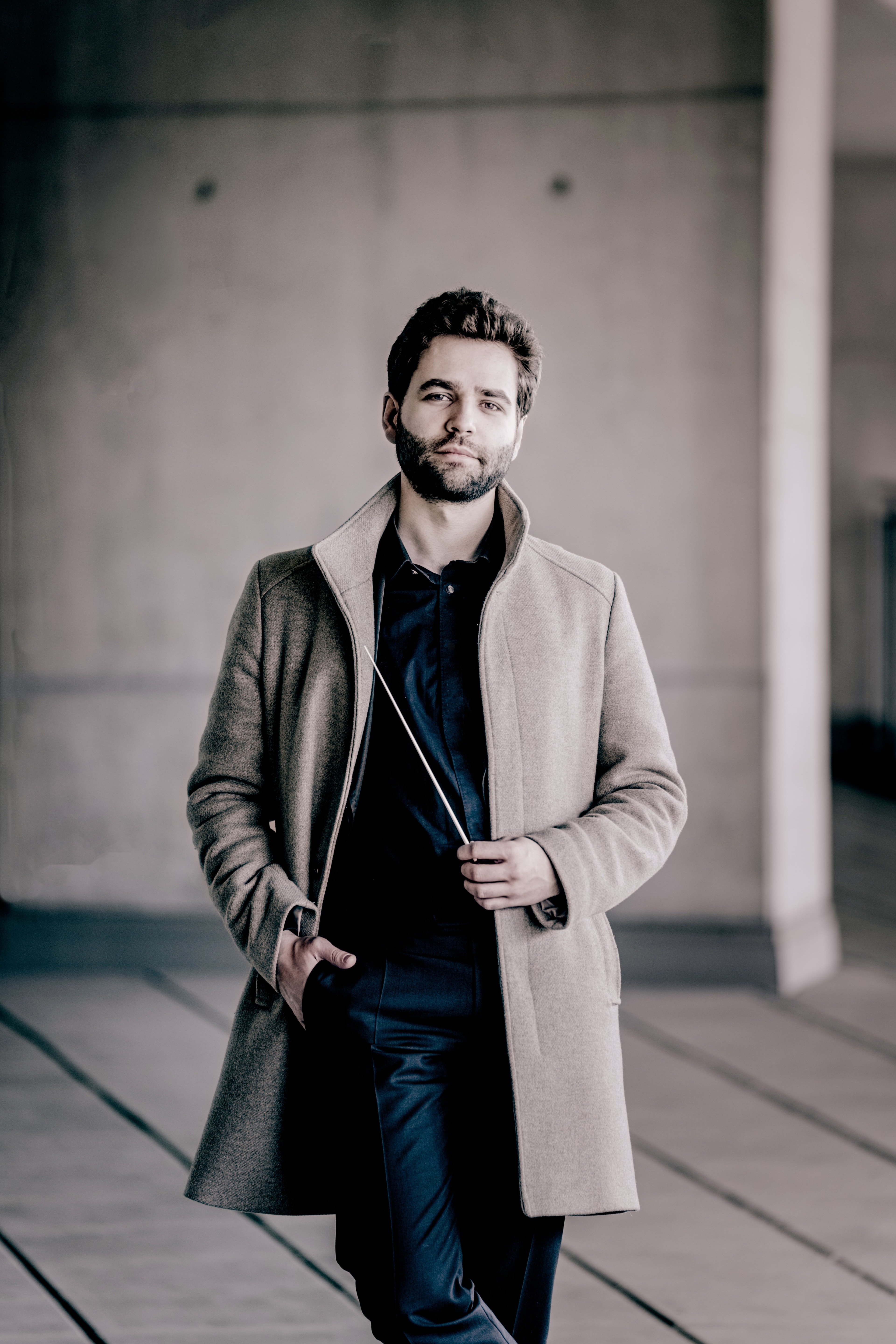 Simon Edelmann in a light coat, holding a baton (photo: Andrej Grilc)